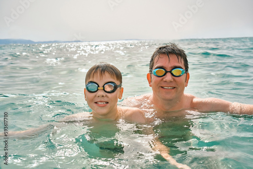 Happy family in swimming goggles, father and son bonding, play, swim in the sea looking at view enjoying summer vacation. Togetherness Friendly concept 