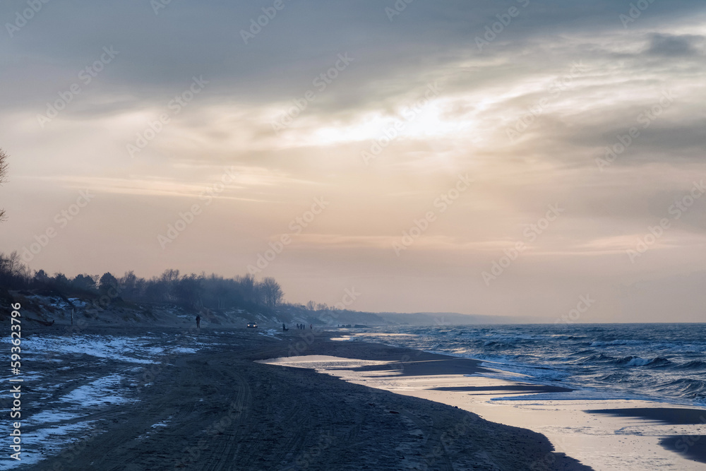 View of the sand beach with the tire marks and footprints on the Baltic Sea coast on the Vistula Spit at the winter time. View of the sand beach with the tire marks and footprints on the Baltic Sea coast on the Vistula Spit at the winter time.