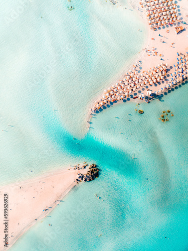 Elafonisi beach in Crete, Greece. Seen from above with the drone looking straight down. Beautiful turquoise water, white sand, and lots of people and parasols.