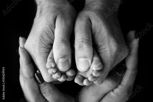 Little baby legs. Children's foot in the hands of mother, father, parents. Feet of a tiny newborn close up. Mom and her child. Happy family concept. Black and white image of motherhood stock photo