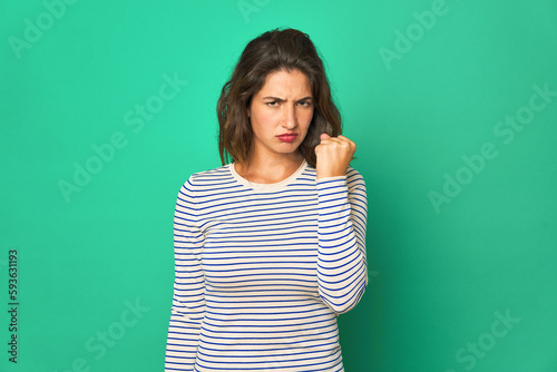 Young caucasian woman isolated showing fist to camera, aggressive facial expression.