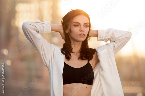 Deamy young woman walking around city in rays of setting sun
