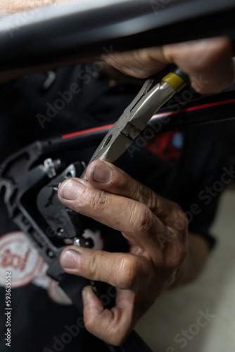 A person with a pliers in his hands is removing a brake pad from a bicycle