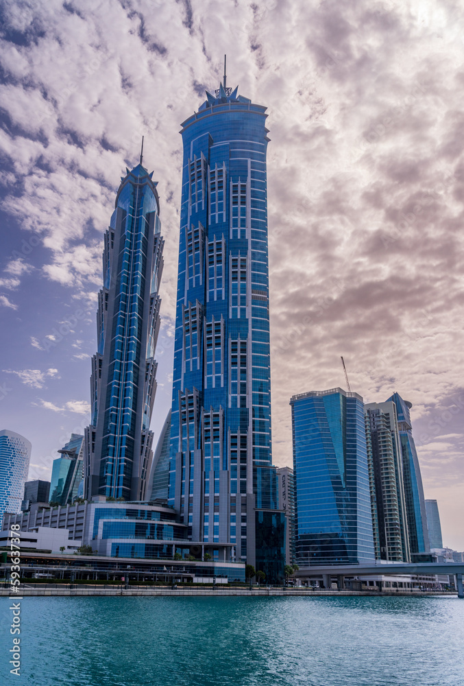 Obraz premium New apartment blocks on the waterfront and cycle path along Dubai Canal with dramatic sky