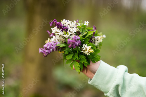 Woman hand with spring bouquet of flowers on forest. Outdoor leisure concept.