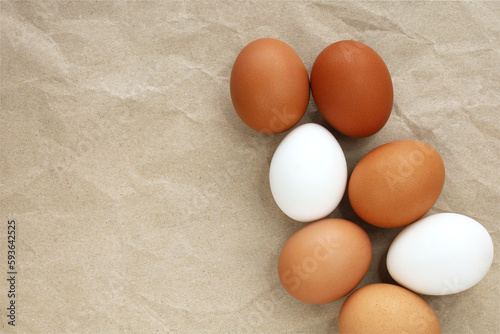 Obraz na płótnie Brown and white eggs on craft paper background. Top view image with copy space. Organic farm eggs, fresh eco products, shopping, Easter concept. w salonie
