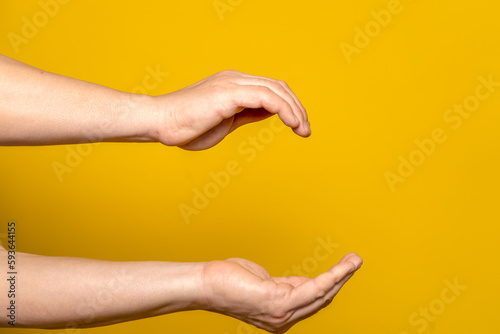 Outstretched arms of robust man with cupped hands in cozy home concept, isolated on yellow background