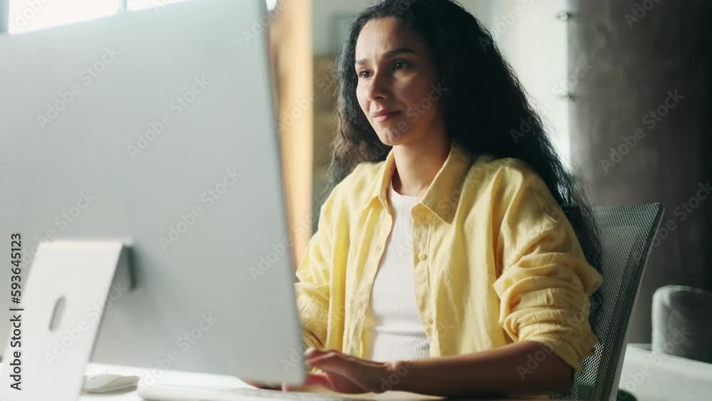 Smiling young hispanic woman relaxing at home or working online typing browsing products in internet store reading news checking email or social media profile on computer and looking at screen indoors