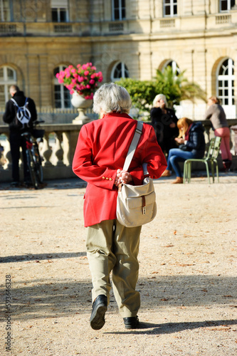 Old lady (unrecognizable people; back view) walking in Luxembourg garden. Urban scene. Paris, France. Senior people lifestyle, elderly wellness, travel and active life concepts.