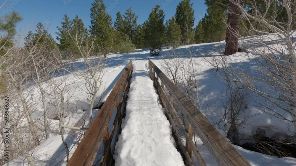 Walking across a snow covered bridge in a forest Walking across a snow covered bridge in a forest