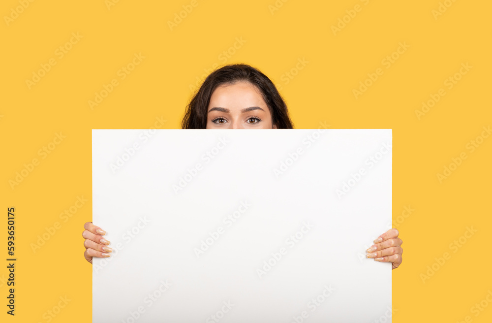 Cheerful millennial middle eastern female showing huge banner with blank space Cheerful millennial middle eastern female showing huge banner with blank space