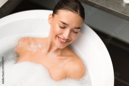 Relaxed Lady Bathing Lying In Water With Foam At Home