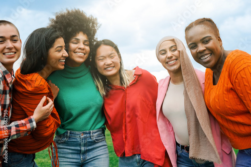 Multiracial group women friends hugging each other outdoors at park city - International people having fun smiling together - Focus on African curvy girl face photo