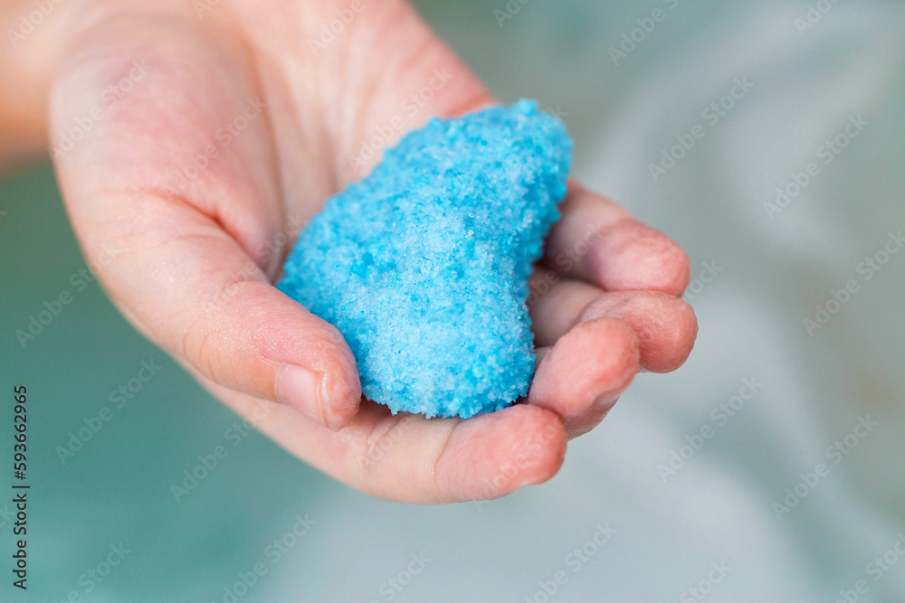 Bath bomb blue with coconut extract in the form of a heart in the hand of a child. Cosmetics and skin care. Copy space for text Bath bomb blue with coconut extract in the form of a heart in the hand of a child. Cosmetics and skin care. Copy space for text