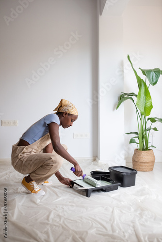 Black woman taking paint near potted plant