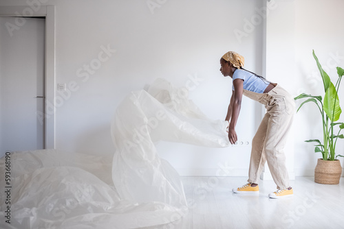 Black painter laying film near door and wall