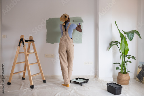 Black painter coloring wall carefully
