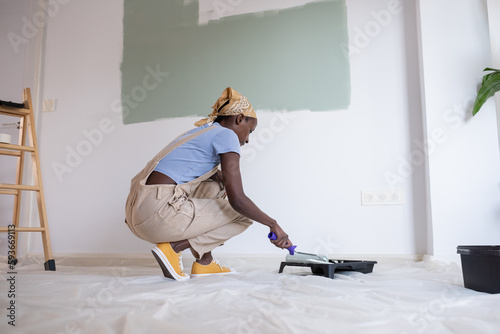 African American woman taking paint with roller