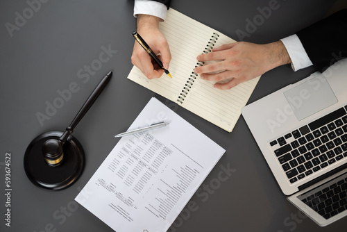 Top view lawyer working or drafting legal document with his laptop at law firm office desk. Gavel hammer for righteous and equality judgment by lawmaker and attorney. Equilibrium photo