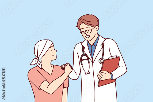 Doctor shakes hands with little cancer patient undergoing chemotherapy to fight cancer. Teenage boy with cancer lost his hair due to radiation exposure and needs support of clinic staff and parents 