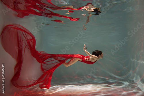 Graceful lady in scarlet dress posing underwater photo