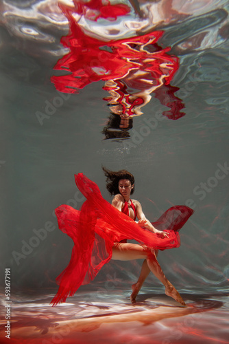 Graceful lady in scarlet dress posing underwater