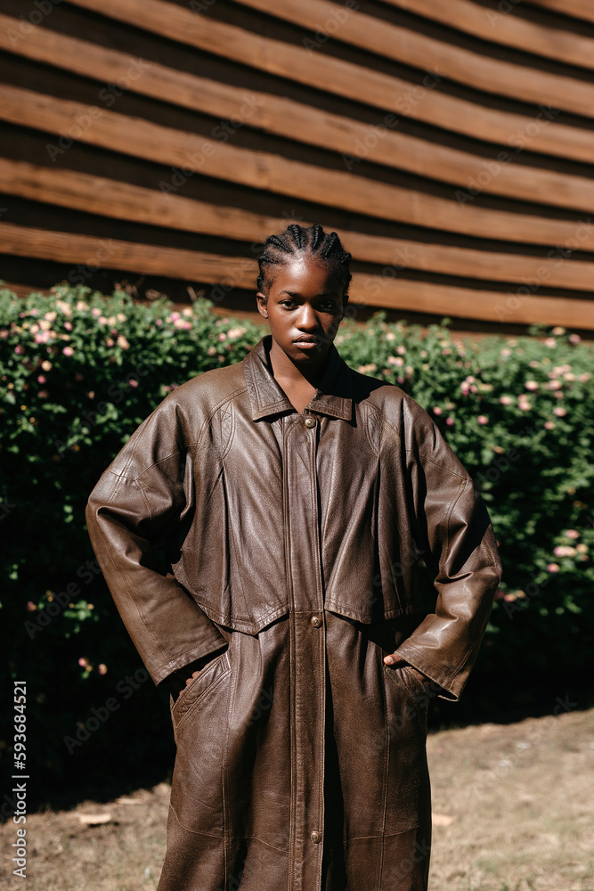 Serious black woman in leather coat with hands in pockets Serious black woman in leather coat with hands in pockets