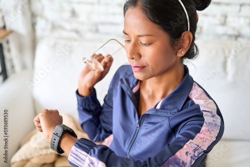 Fotografi Timeless and Reliable: Young Indian woman checks her watch for punctuality and style