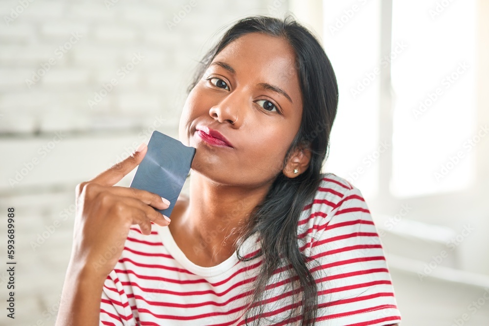 Thoughtful young Indian woman holding credit card Thoughtful young Indian woman holding credit card