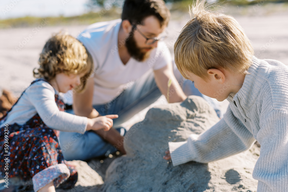 Happy family playing at a beach together building a sand castle