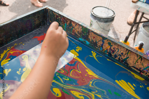 Child's hand doing colorful Suminagashi ink painting photo