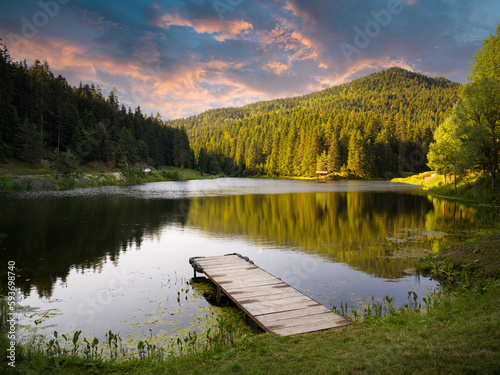 Fototapeta Naklejka Na Ścianę i Meble -  Sunset time on a beautiful forest lake. Wooden empty pier on the lake