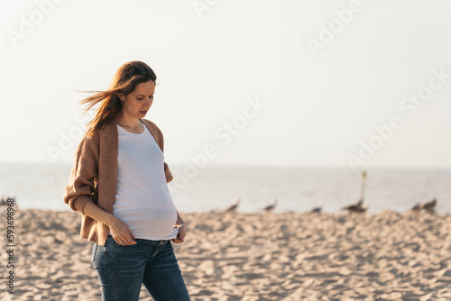 woman with her hair flying around looking at her pregnant bel photo