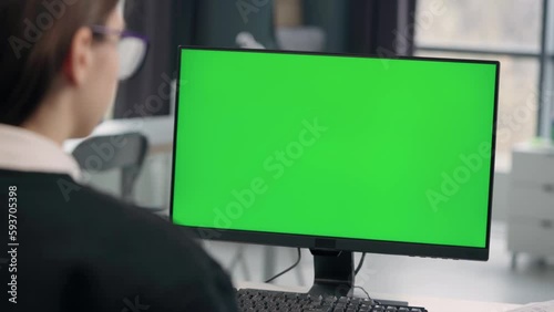 Young Girl Working At Computer With Green Mock Up Screen in Office. Close Up Desktop Computer Monitor with Mock Up Green Screen Chroma Key Display