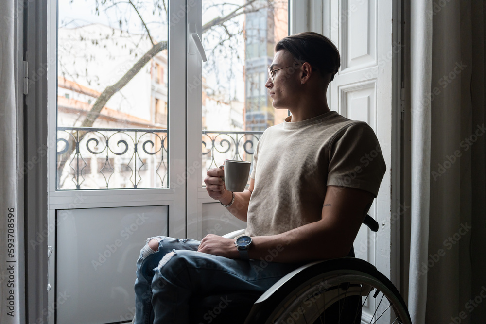 Young Man User Of A Wheelchair Looks Out The Window Young Man User Of A Wheelchair Looks Out The Window