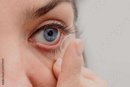 Crop woman putting on contact lens photo