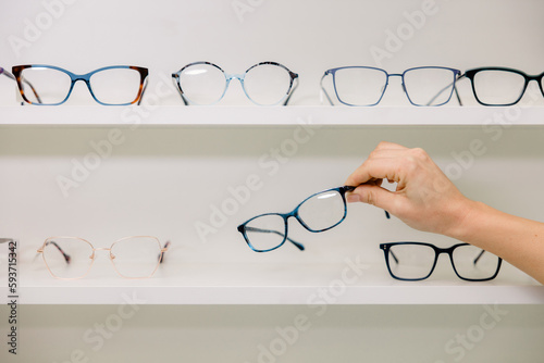 Anonymous woman choosing glasses in optic shop