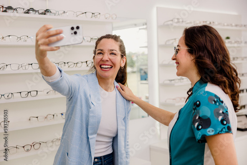 Cheerful woman taking selfie on smartphone in opticians shop photo