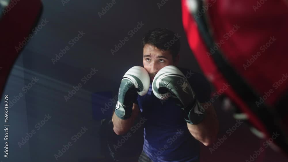 Training with a boxing coach in the training hall. Caucasian athlete kicks with gloves actively. Hard work and preparation for sparring and fighting. High quality 4k footage Training with a boxing coach in the training hall. Caucasian athlete kicks with gloves actively. Hard work and preparation for sparring and fighting. High quality 4k footage