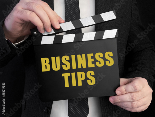 A businessman holds up a сlapperboard with text Business Tips photo