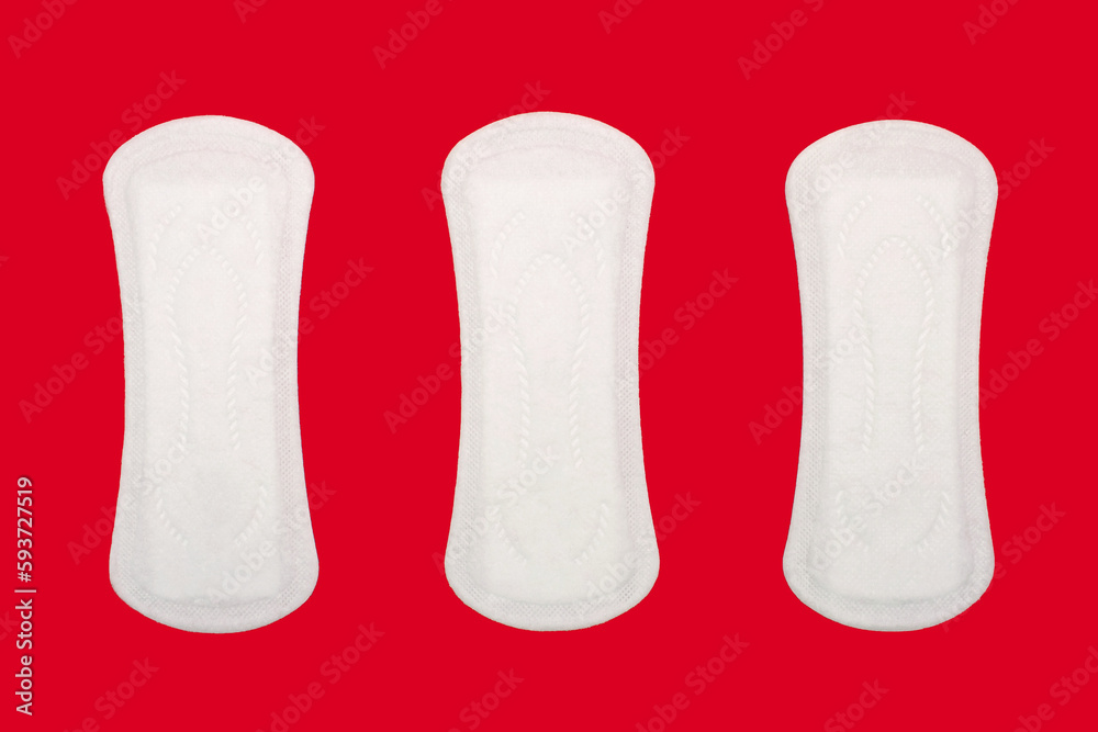 Three feminine hygiene menstrual pads are located on a red background. Feminine hygiene product in the form of sanitary pads. Clean menstrual pads ready to use. Women's daily sanitary napkins Three feminine hygiene menstrual pads are located on a red background. Feminine hygiene product in the form of sanitary pads. Clean menstrual pads ready to use. Women's daily sanitary napkins