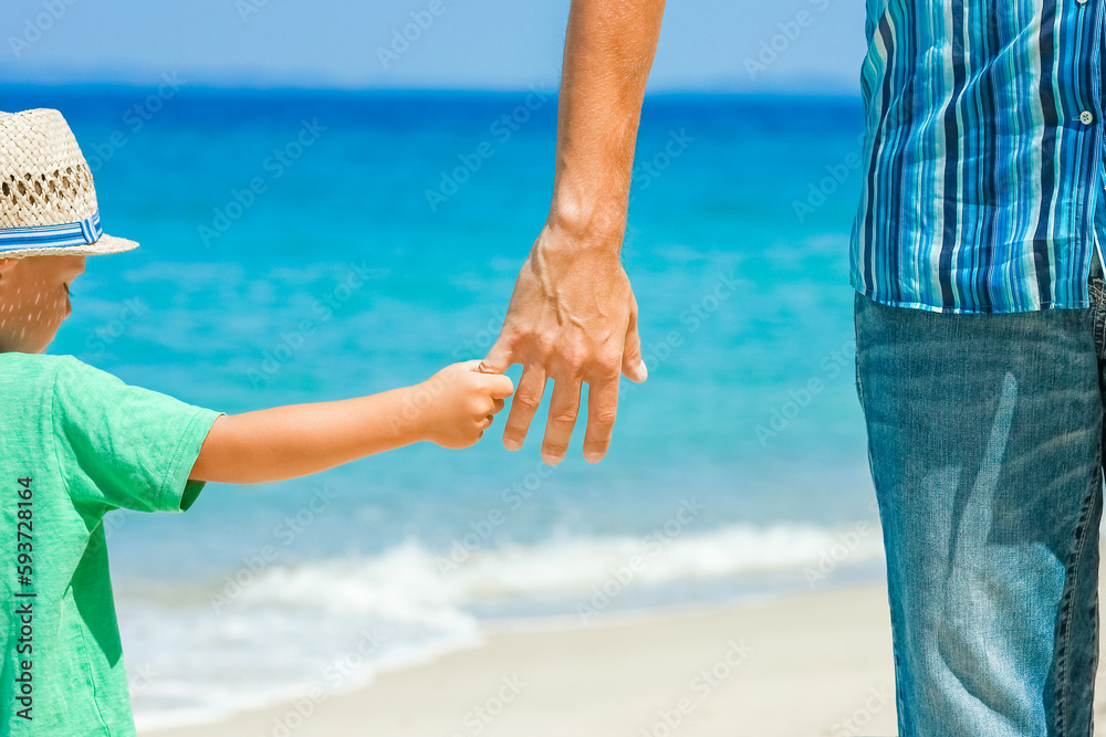 A Hands of a happy parent and child on the seashore on a journey trip in nature