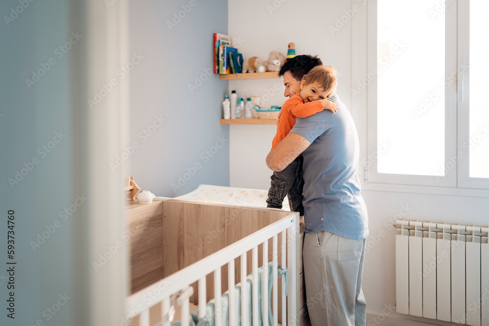 Father hugging a child next to a cradle Father hugging a child next to a cradle