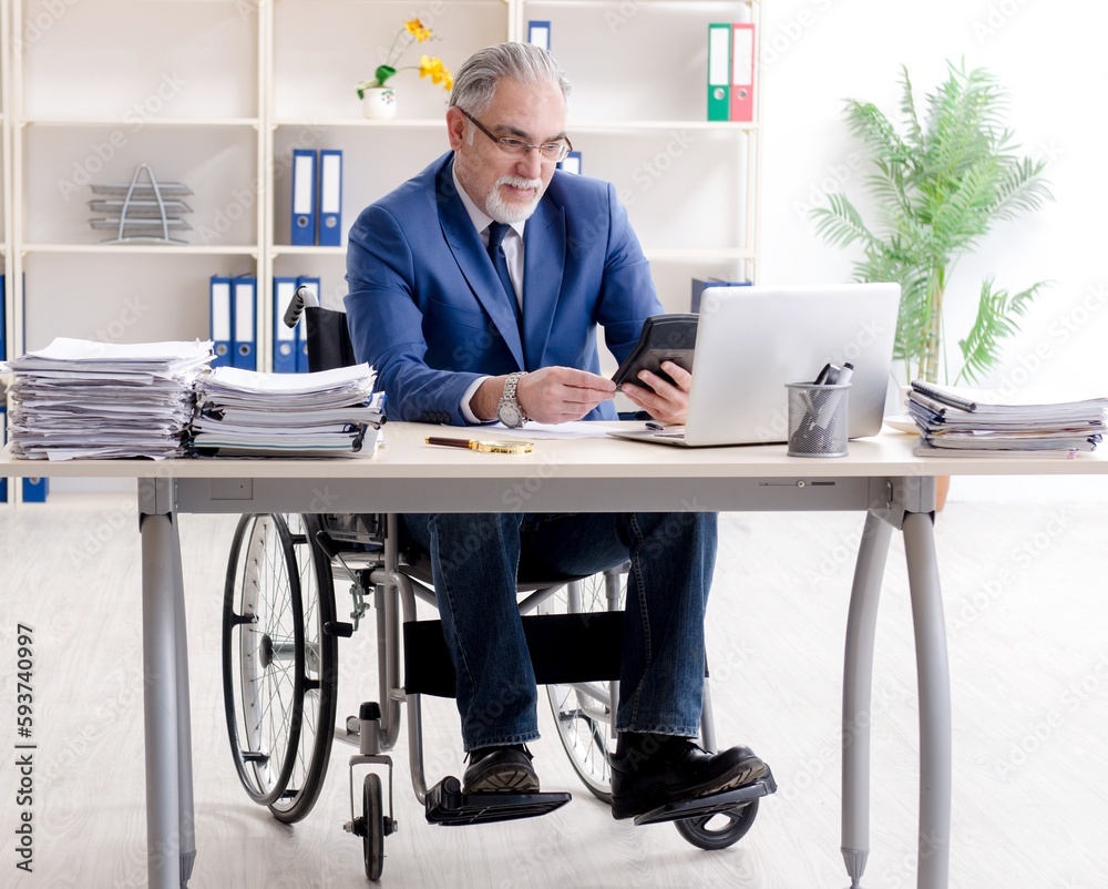 Aged employee in wheelchair working in the office Aged employee in wheelchair working in the office