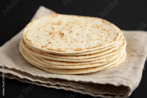 Stack of Whole Wheat Flour Tortillas on a black background, side view. Close-up.