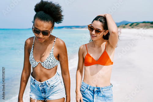 Happy diverse friends walking on beach