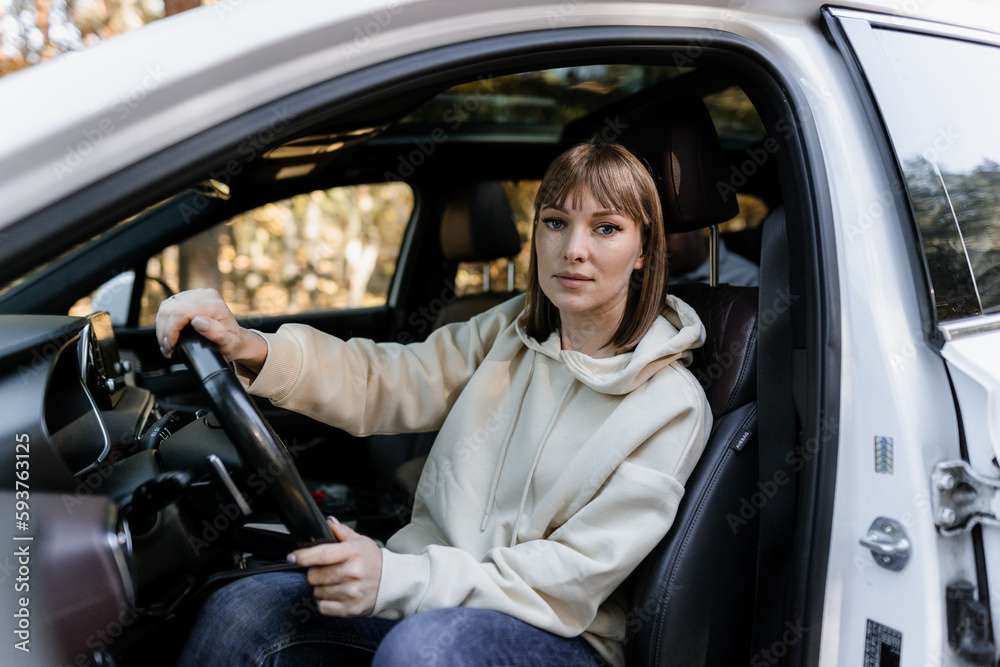 Woman smiling looking at the camera sitting at the wheel of a car Woman smiling looking at the camera sitting at the wheel of a car