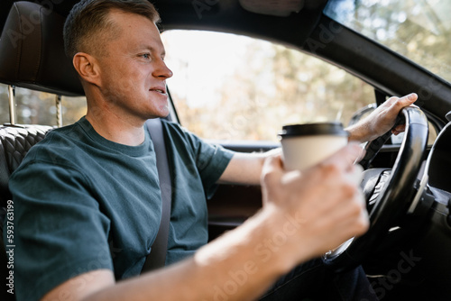A man drinks from a disposable cup while driving