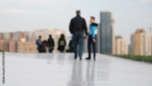 A father and son walk hand-in-hand through a bustling urban cityscape of unique, tall skyscrapers towards an uncertain future. photo