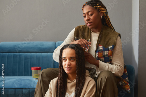 Women sitting on a livingroom braiding  their hair  photo